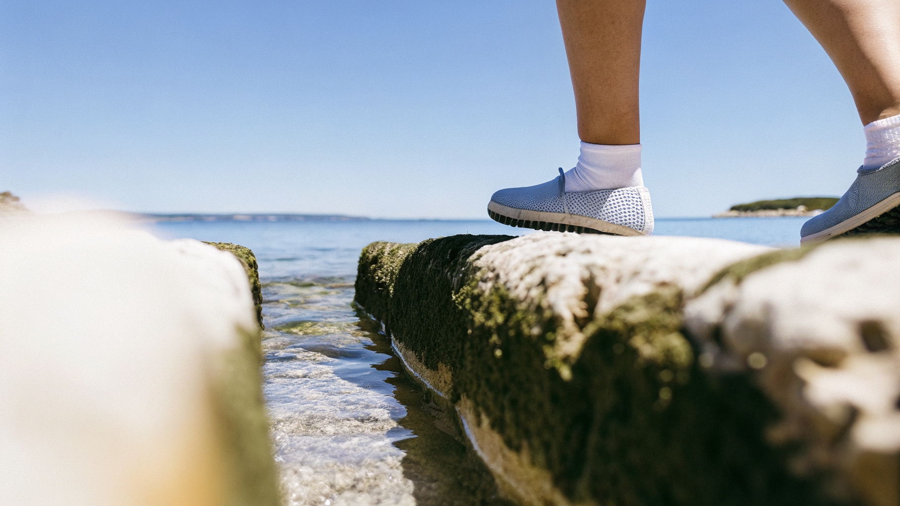 Feet in water shoes entering the sea over rocks on a Croatian beach
