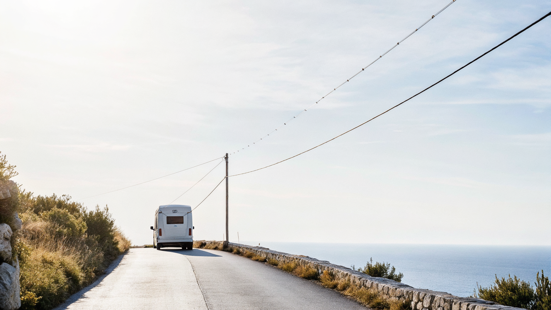 Narrow coastal hairpin road on Croatia's Adriatic Highway with a camper van ahead