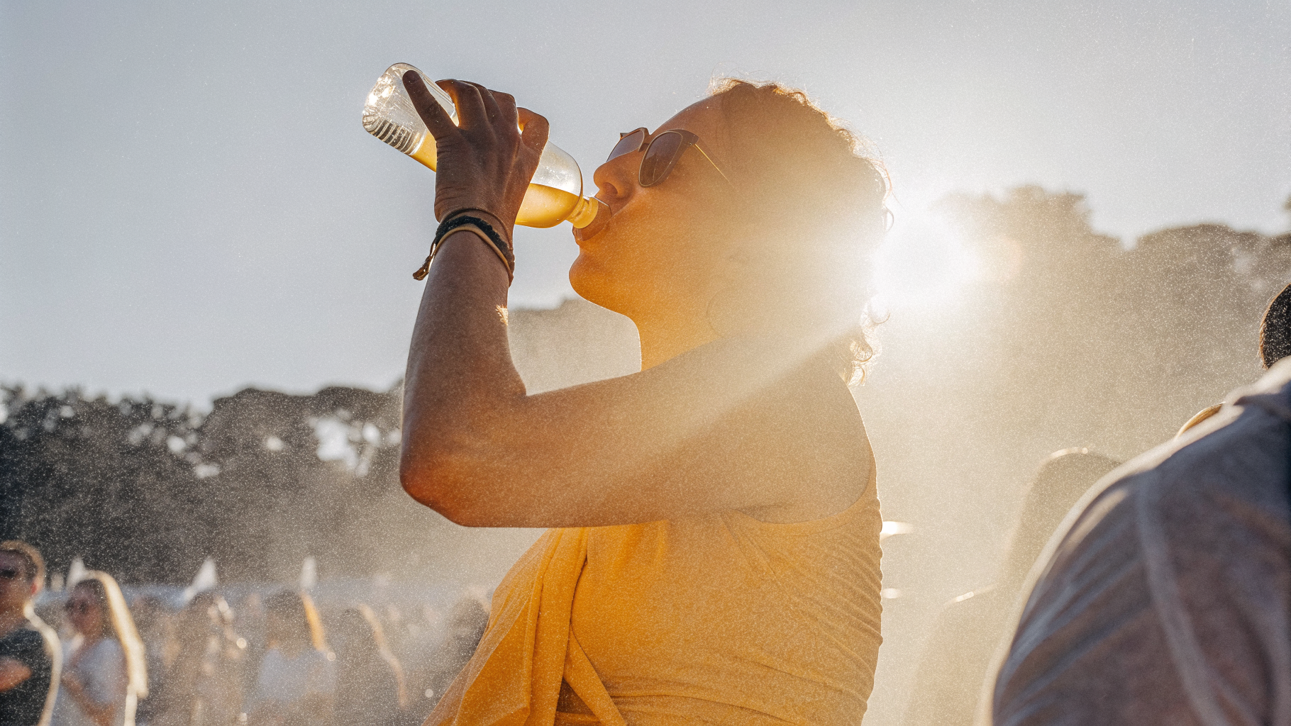 Festival-goer drinking water in the sun to stay hydrated in a crowd