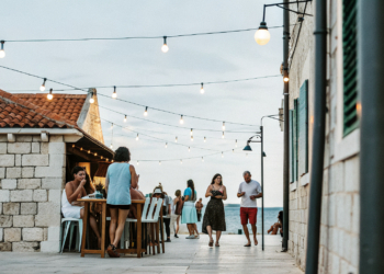 Friends enjoying drinks on an old-town bar terrace at dusk on the Croatian coast