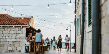 Friends enjoying drinks on an old-town bar terrace at dusk on the Croatian coast