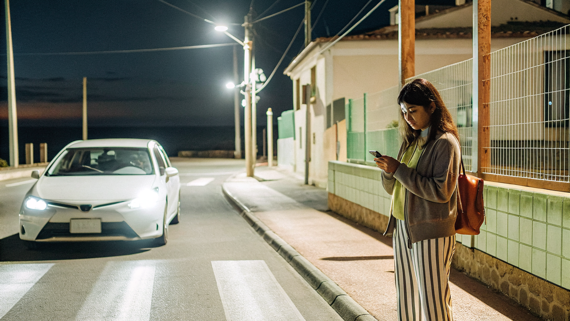 A traveller using a ride-hailing app to get home safely at night in a Croatian coastal town