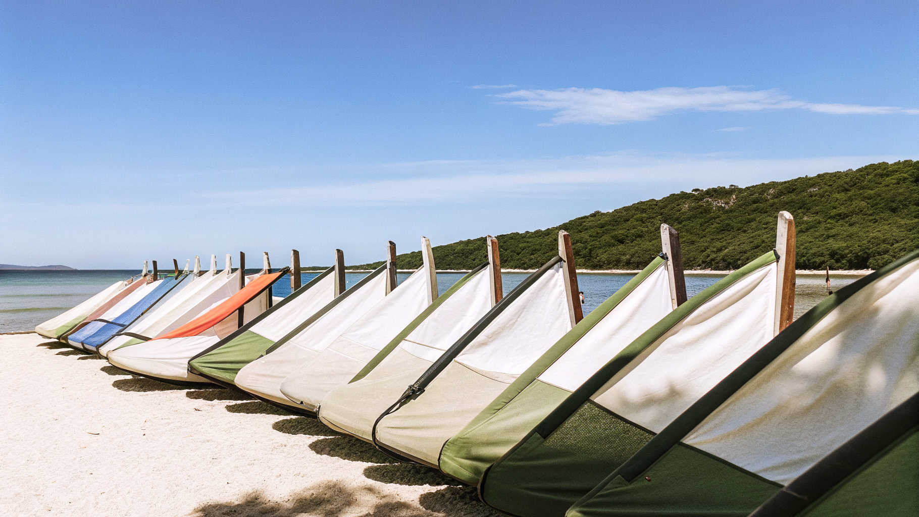 Rigged windsurf boards and sails lined up on a Croatian beach on a breezy afternoon