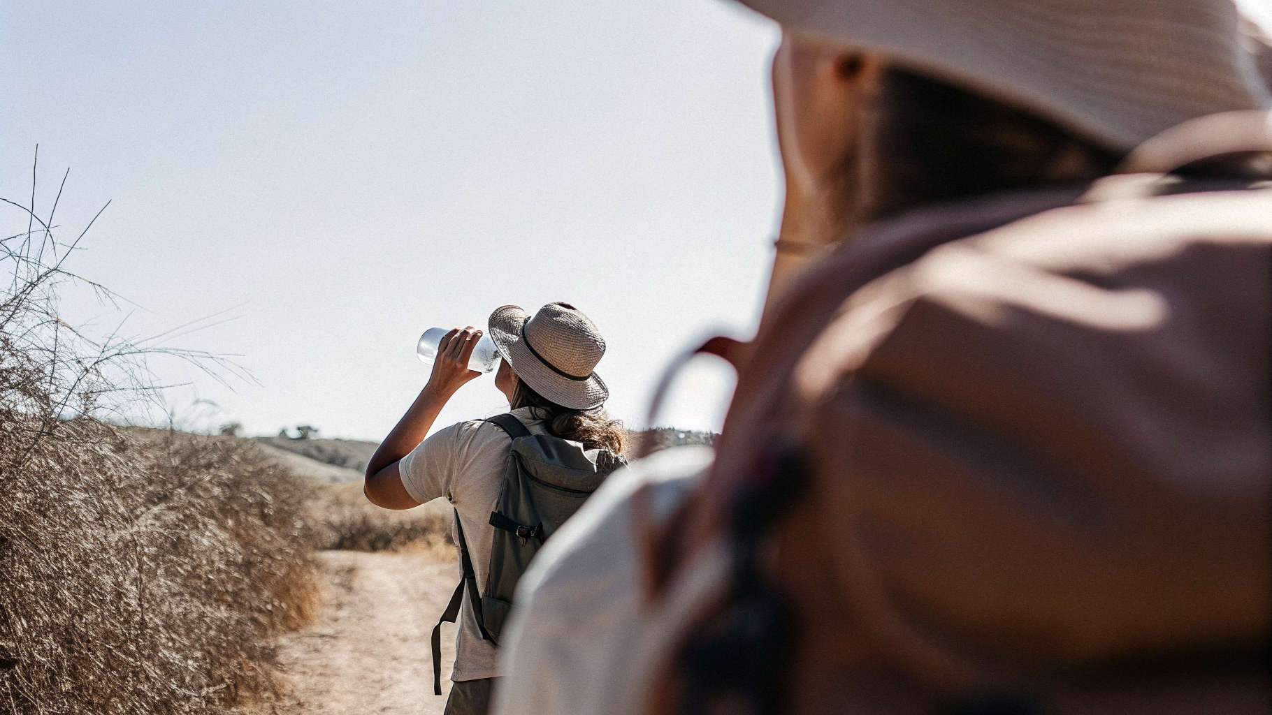 Hiker drinking water on a shadeless sun-baked canyon trail in a Croatian national park