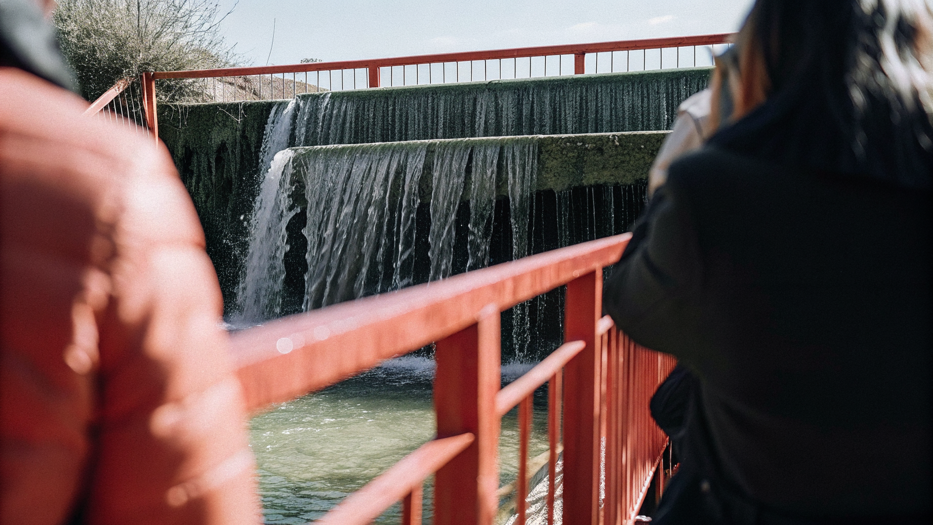 Visitors watching a travertine waterfall from a viewing platform where swimming is not allowed