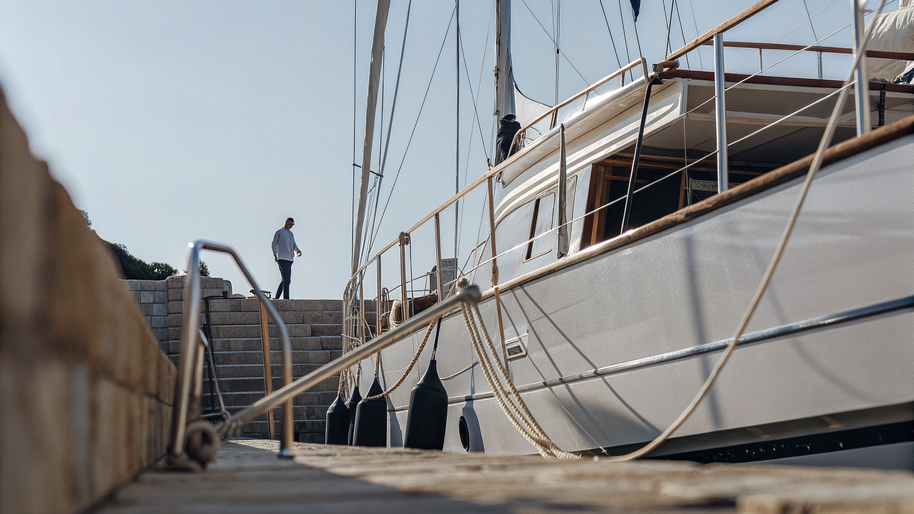 A yacht moored stern-to on a stone quay in a small Croatian harbour at dusk