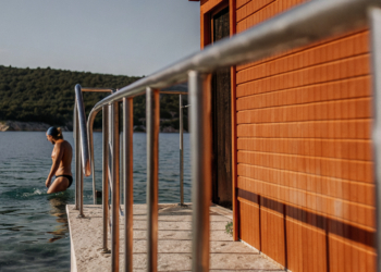 Swimmer entering clear Adriatic water from a rocky Croatian cove