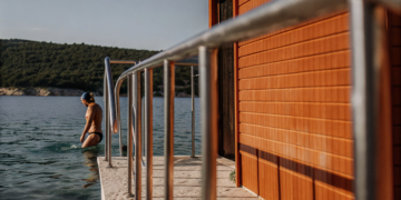 Swimmer entering clear Adriatic water from a rocky Croatian cove