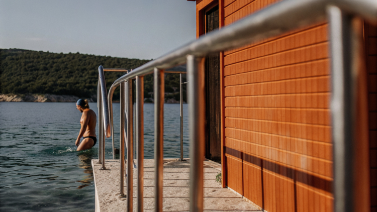 Swimmer entering clear Adriatic water from a rocky Croatian cove