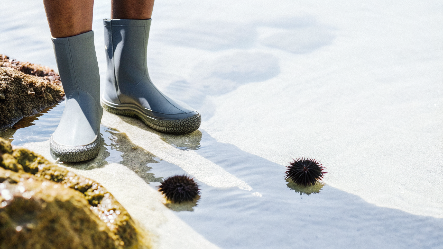 Water shoes on pebbles beside sea urchins in shallow Adriatic water in Croatia