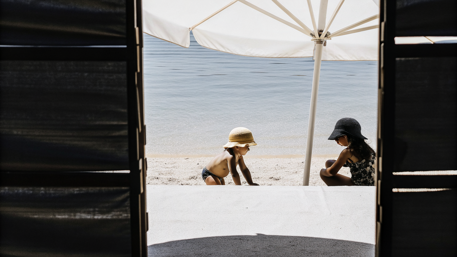 Children in water shoes and sun hats playing at a shaded Croatian pebble beach under supervision