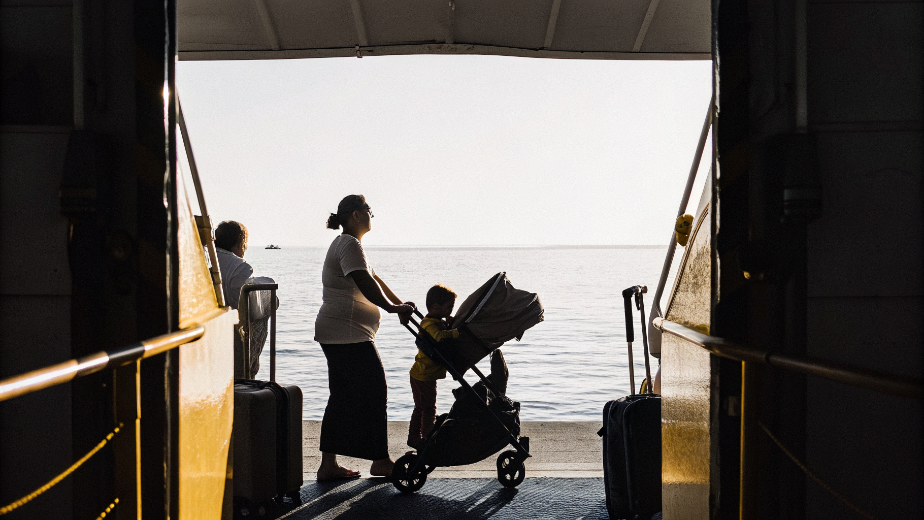 Parent with a folded stroller and child boarding a Croatian island ferry at a harbour