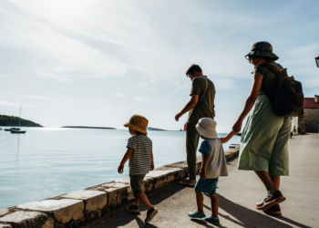 Family with young children walking a sunny Croatian seafront promenade beside calm Adriatic water