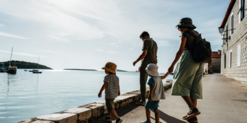 Family with young children walking a sunny Croatian seafront promenade beside calm Adriatic water