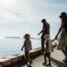 Family with young children walking a sunny Croatian seafront promenade beside calm Adriatic water