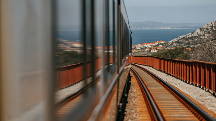 Illustration of a modern hybrid train travelling from Zagreb through the mountains toward Split